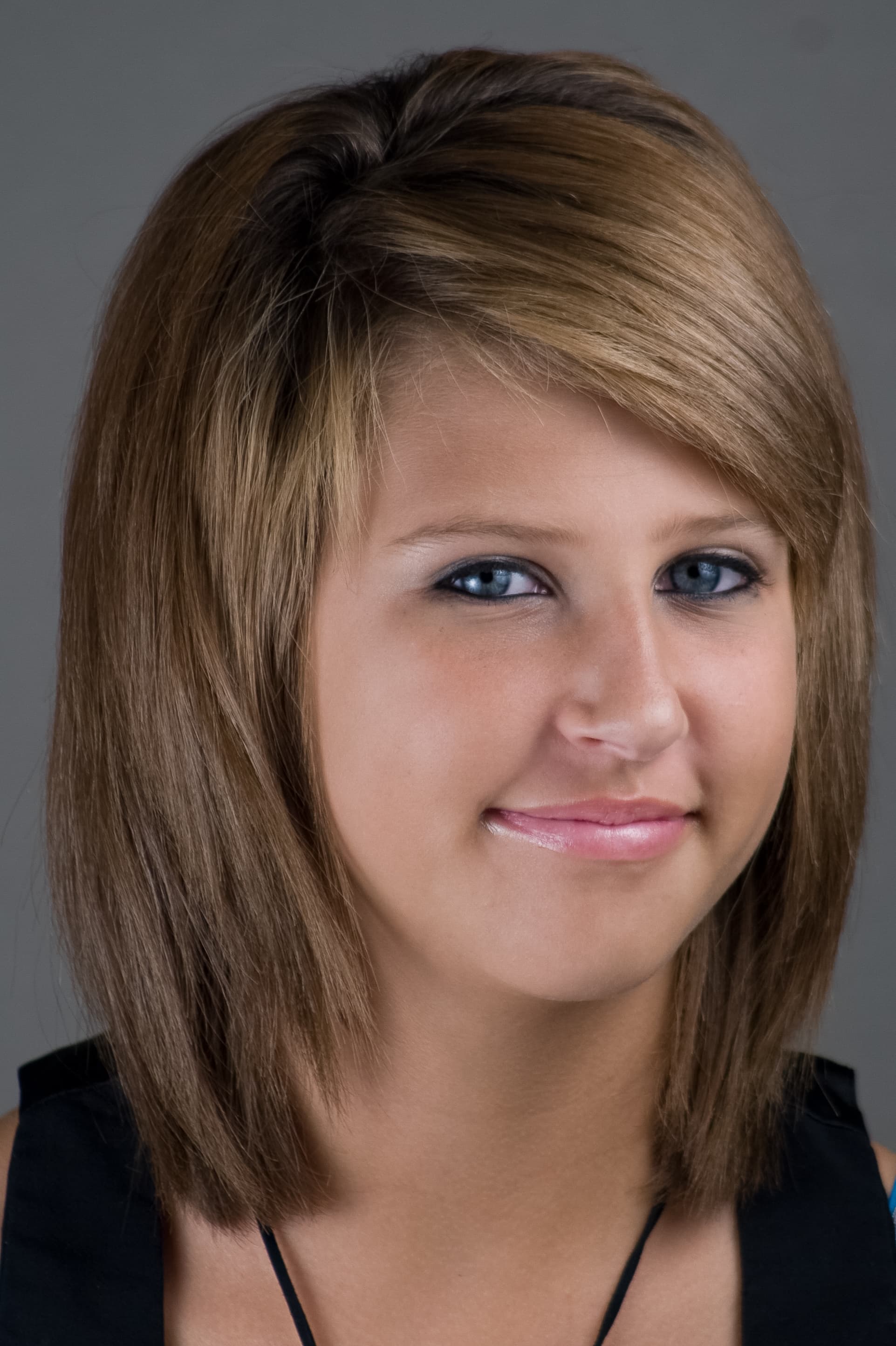Close-up portrait of a smiling young woman with light brown hair and blue eyes.