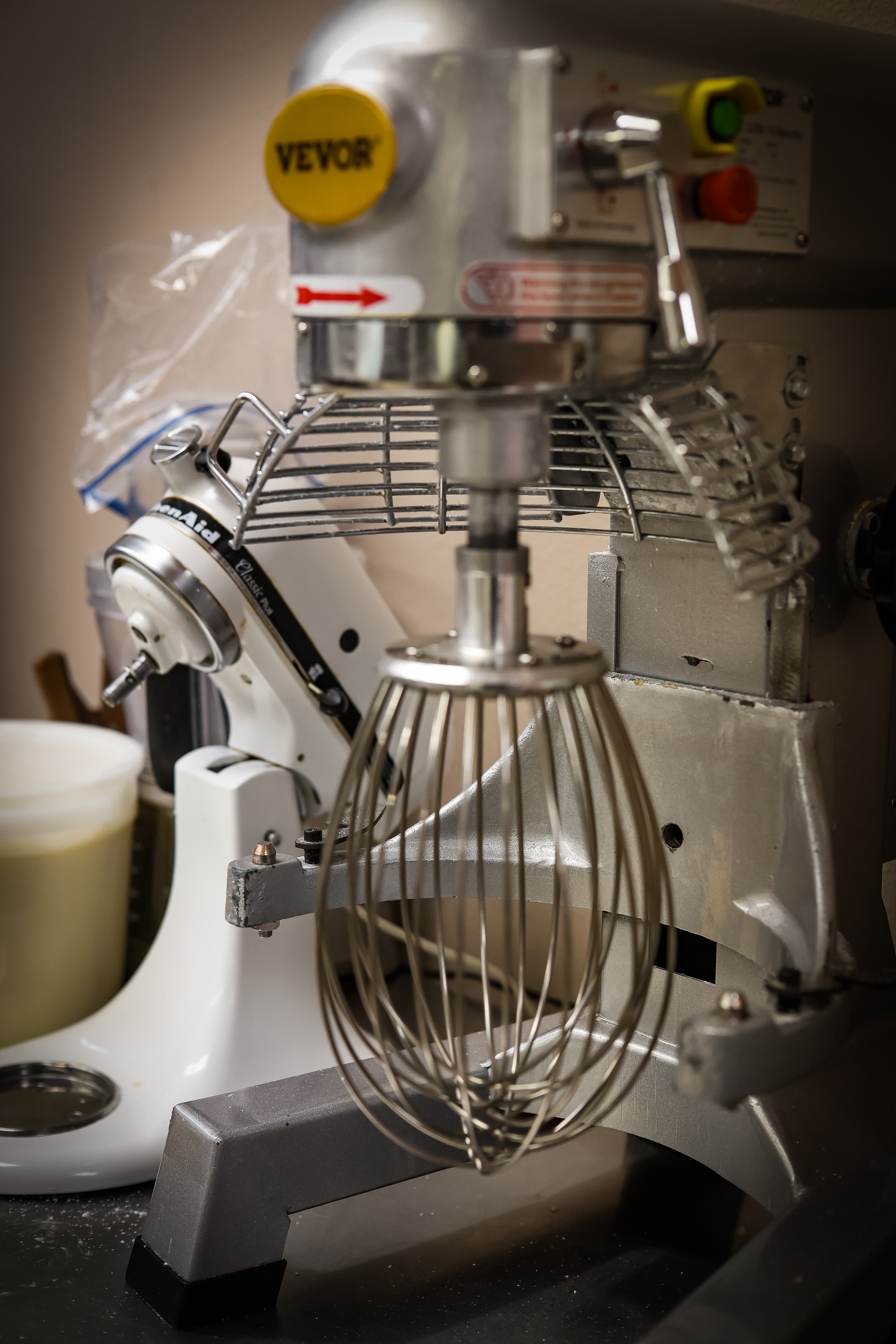 Large silver VEVOR commercial stand mixer with a wire whisk attachment and protective metal cage.