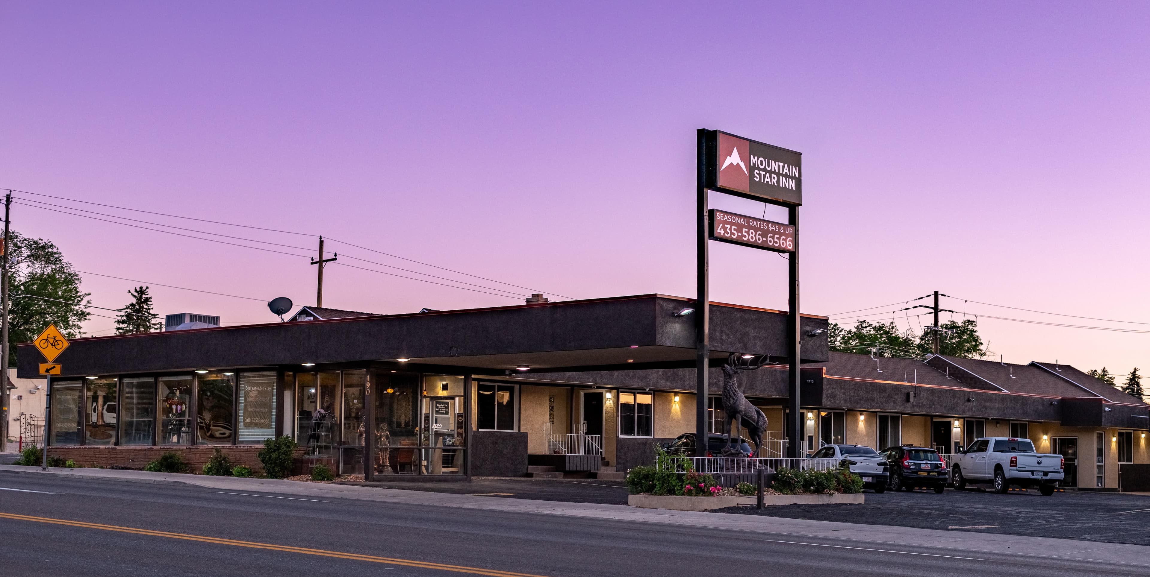 Mountain Star Inn motel exterior at twilight with a purple sky and deer statue.