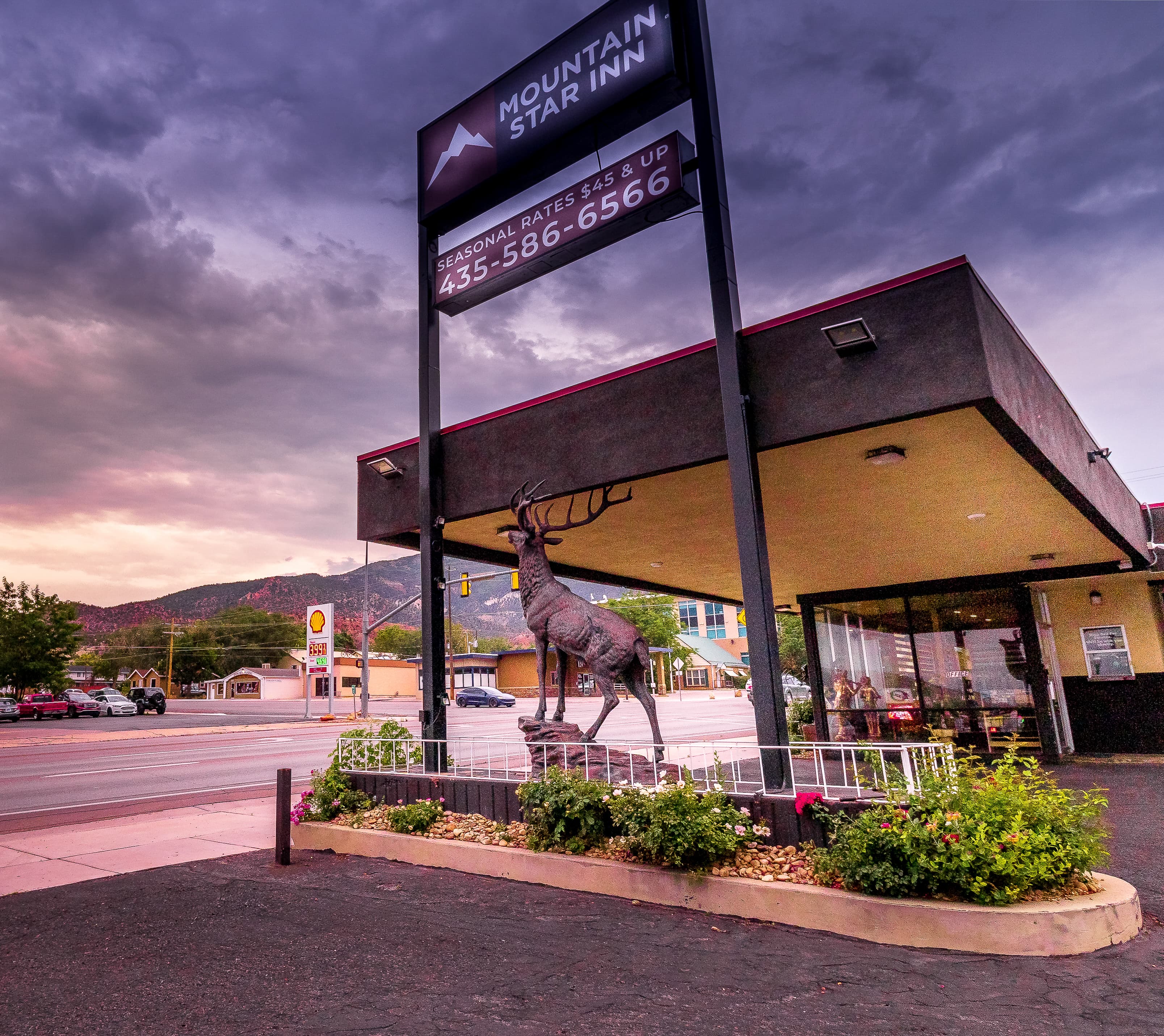 Elk statue stands under the Mountain Star Inn sign against a dramatic, stormy sunset sky.