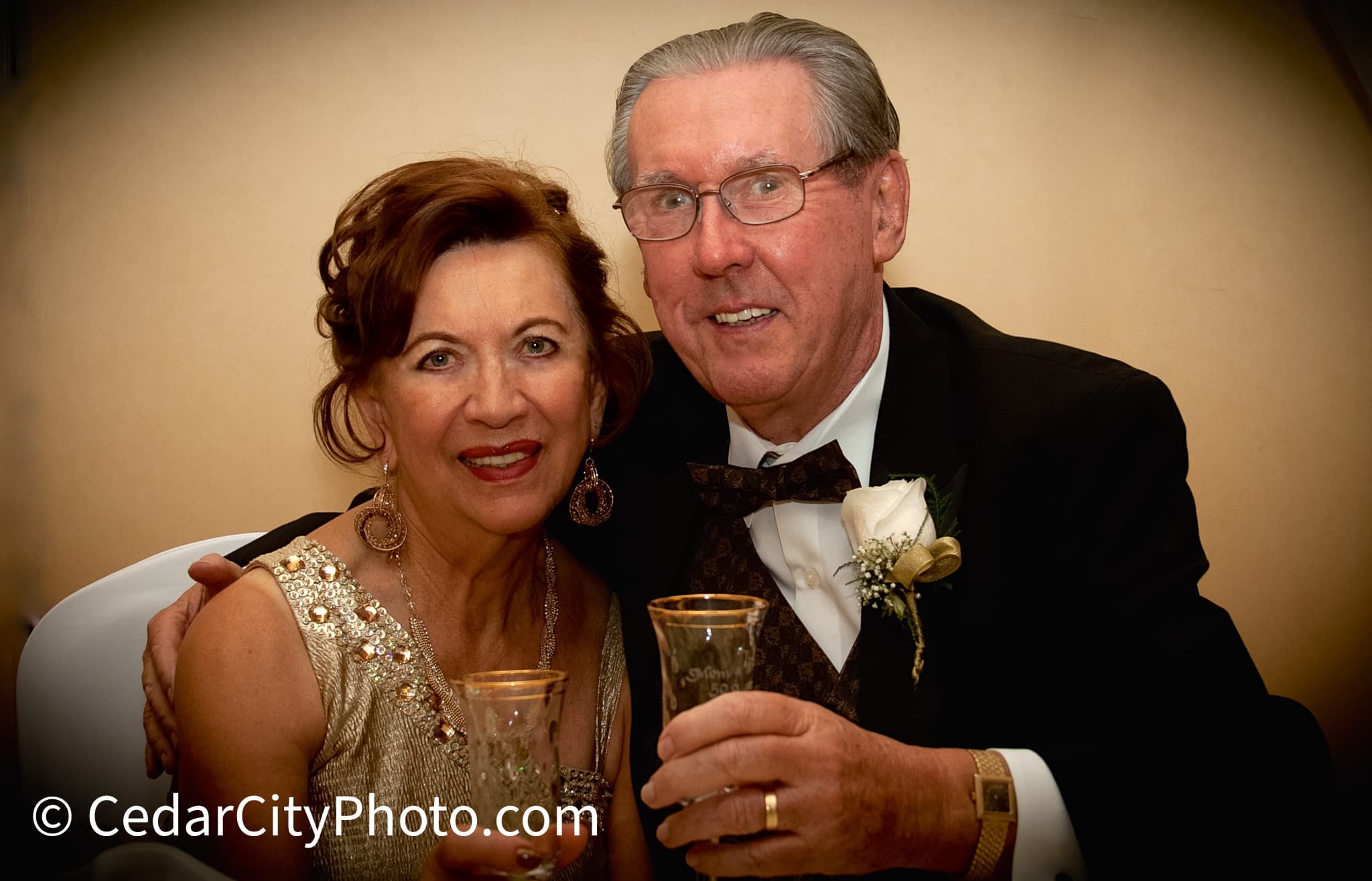 Senior couple in formal attire smiling and holding glasses during a celebratory toast.
