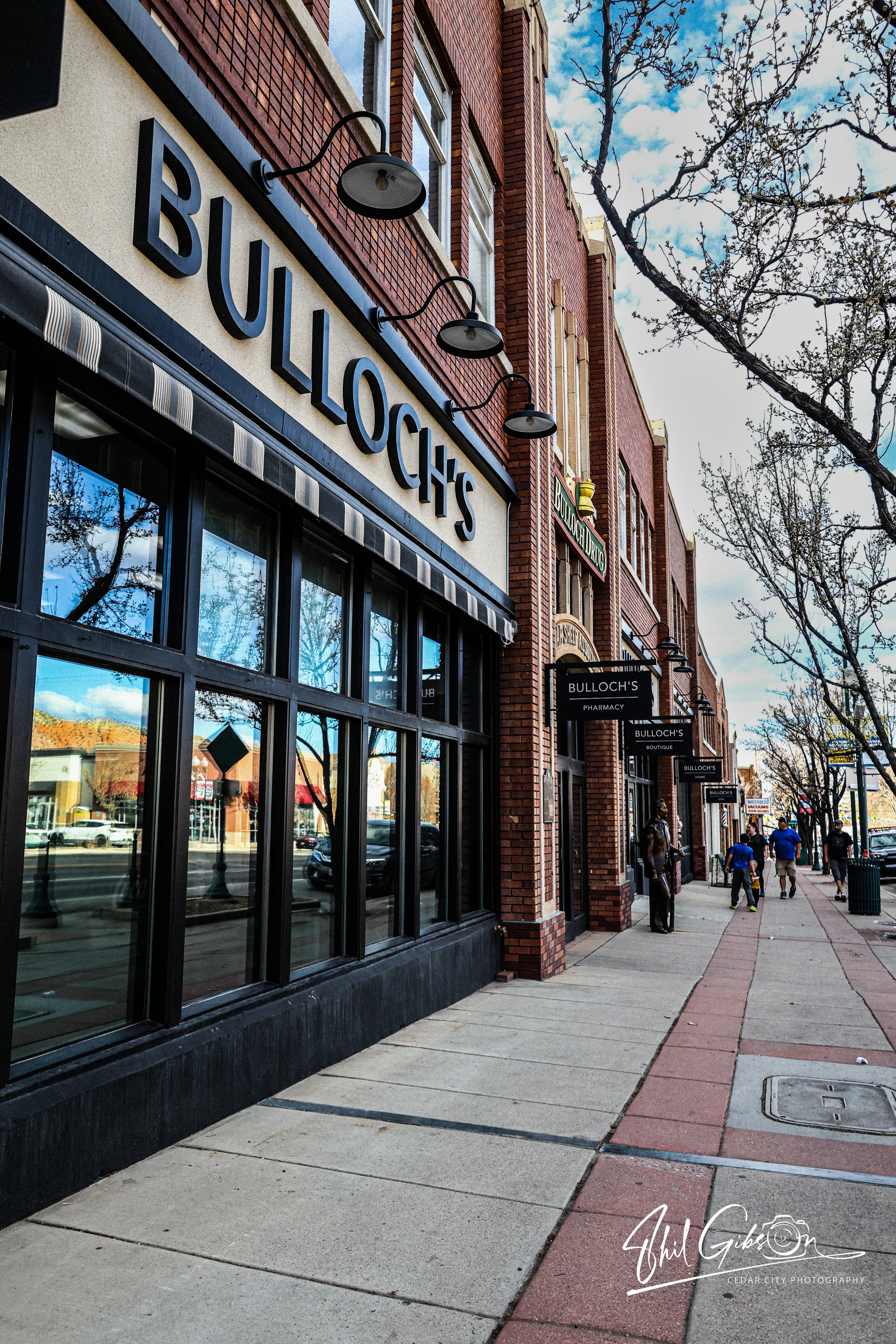 Bulloch's storefront with brick architecture, large windows, and black gooseneck lamps along a sidewalk.